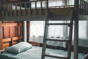 a bunk bed with a ladder next to a window at Yor Song Hostel in Pai