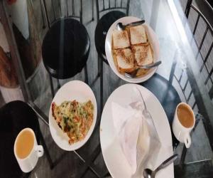 een tafel met borden en kopjes koffie bij Dhe Kyi Khang by Magwave Hotels-100 Mts from MG Marg in Gangtok