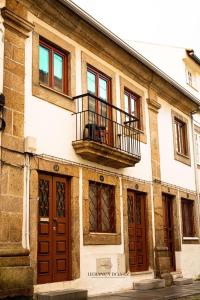 an old building with a balcony and doors at Apartamentos Herança do Vez in Arcos de Valdevez