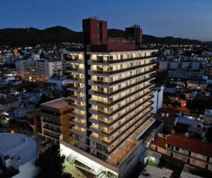 un edificio alto con luces encendidas en una ciudad en Edificio Leonardo Apart Centro en Villa Carlos Paz
