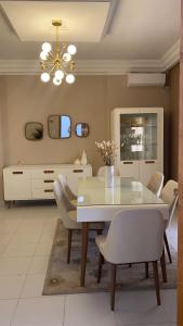 a dining room with a white table and chairs at Modern Apartment High Standards in Monastir