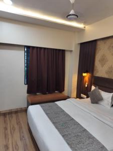 ein Hotelzimmer mit einem Bett und einem Fenster in der Unterkunft HOTEL RJ RESIDENCY in Ahmedabad