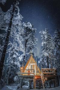 una cabaña de madera en la nieve por la noche en Cozy a-frame in the woods, en Enontekiö