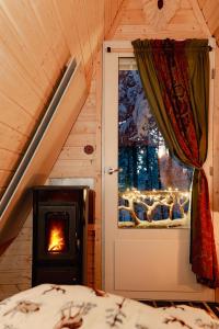 a bedroom with a stove in a room with a window at Cozy a-frame in the woods in Enontekiö