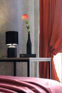 a vase with a flower on a table with a lamp at Round Garden Hotel in Tbilisi City