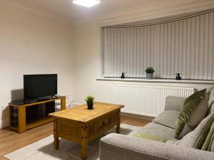 a living room with a couch and a tv at Boss Breaks- Newcastle in Lemington