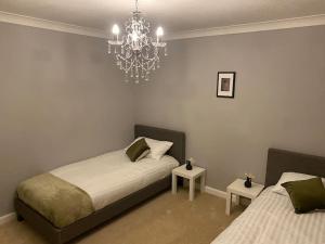 sypialnia z 2 łóżkami i żyrandolem w obiekcie Boss Breaks- Newcastle w mieście Lemington