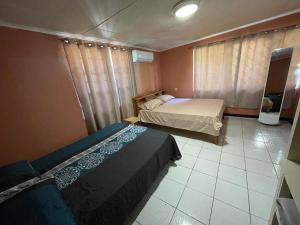 a bedroom with two beds and a tiled floor at Osso fu mi ati (huis van mijn hart) in Paramaribo