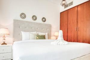 杜拜的住宿－Lovely 1 bedroom apartment for vacations，卧室配有白色的床和墙上的2个钟