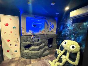 a room with a cave with a rock wall and an aquarium at Holy Planet in Tokyo