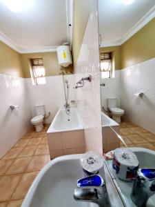 La salle de bains est pourvue d'une baignoire, d'un lavabo et de 2 toilettes. dans l'établissement OCTA HOMES, à Kampala