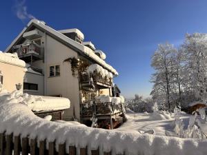 a house covered in snow next to a fence at Ferienwohnung DAS SCHELLENWIES in Murnau in Murnau am Staffelsee