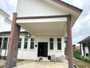 ein weißes Haus mit einer schwarzen Tür und Stühlen in der Unterkunft Homestay Ashad in Kuantan