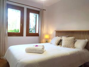 a bedroom with a large white bed with two pillows at La casa de las Palmeras in Muntanya la Sella