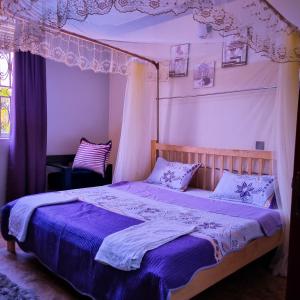a bedroom with a canopy bed with purple sheets at OCTA HOMES in Kampala