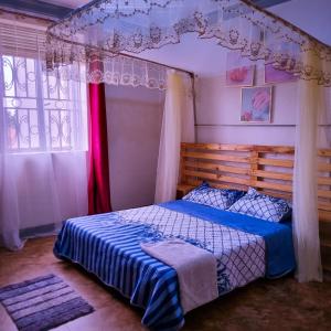 a bedroom with a canopy bed and a window at OCTA HOMES in Kampala