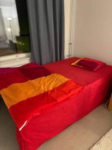 1 cama con sábanas rojas y naranjas en una habitación en apartment, en Lappeenranta