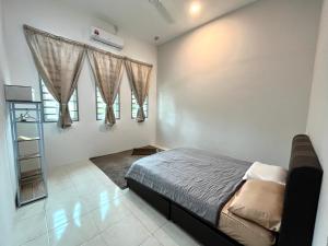 a bedroom with a bed and two windows at Homestay Ashad in Kuantan