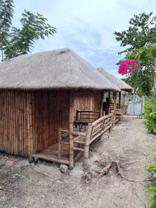 a wooden hut with a thatch roof and benches at Lionfish Backpackers Hostel Malapascua in Daanbantayan