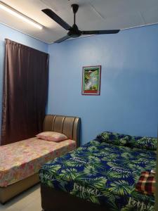 a bedroom with two beds and a ceiling fan at RizqFateh Homestay in Kluang