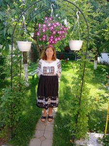 Una donna è in piedi in un giardino con dei fiori di Apartamente Bucegi a Rîşnov