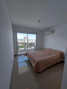 a bedroom with a bed and a large window at Edificio Leonardo Apart Centro in Villa Carlos Paz
