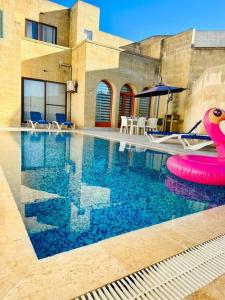 - une piscine avec un jouet rose dans l'eau dans l'établissement Dawlet ix-Xemx Gozo Farmhouse, à Kerċem