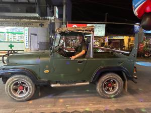 a man is sitting in a green jeep at Khmer rooms in Siem Reap