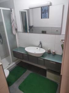 a bathroom with a sink and a mirror and green mats at Cozy Apartment near tram station in Zagreb