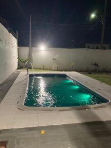 una piscina por la noche con una fuente de agua en POUSADA RECANTO DULE en Guarapari