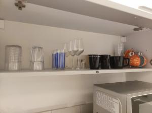 a shelf with wine glasses and utensils on it at Cozy Apartment near tram station in Zagreb
