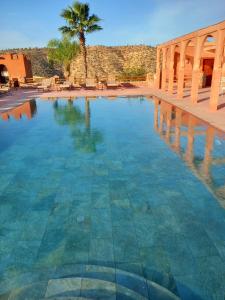 une piscine avec un palmier en arrière-plan dans l'établissement Ecolodge Atlas Kasbah, à Agadir