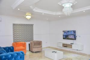 a living room with chairs and a tv and a chandelier at Orchids Service apartments in Lagos
