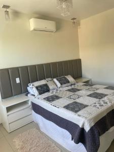 a bedroom with a bed with a blanket and pillows at Temporada Cabo Frio in Cabo Frio