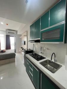eine Küche mit grünen Schränken, einem Waschbecken und einem Bett in der Unterkunft Sea View Studio Flat at Losari Beach in Makassar