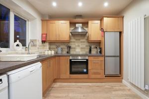 a kitchen with wooden cabinets and stainless steel appliances at Richmond House - 5 Bed, Sleeps 10, Great for Workers & Groups, Netflix & FREE Parking in Manor