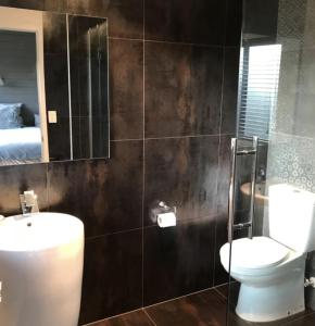 a bathroom with a toilet and a sink and a mirror at Garden Oasis in the heart of Pāpāmoa in Tauranga +19 photos