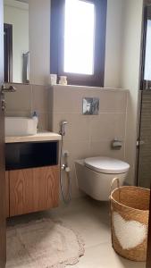 a bathroom with a sink and a toilet and a window at Sifah Beach Cottage in As Sīfah