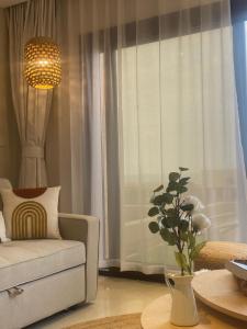 una sala de estar con una silla y un jarrón de flores en Sifah Beach Cottage en As Sīfah