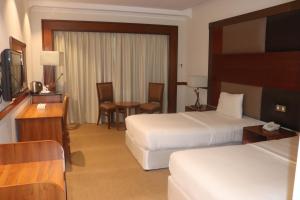 um quarto de hotel com duas camas e uma mesa em GSS Avenue Hotel Ex Delmon Hotel em Dubai