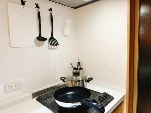 a kitchen with a stove with a frying pan and utensils at Retreat Tachibana 旅趣・橘 in Osaka