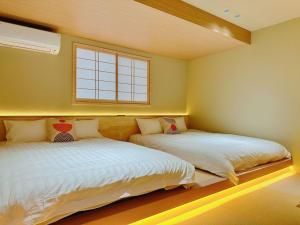 two beds in a bedroom with a window at Retreat Tachibana 旅趣・橘 in Osaka