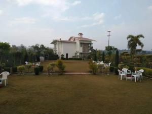 una casa con un patio con sillas y mesas blancas en Corbett Wild Nature View Resort, en Rāmnagar
