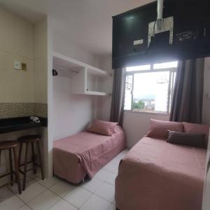 a small room with two beds and a window at Kitnet no centro de Guarapari in Guarapari