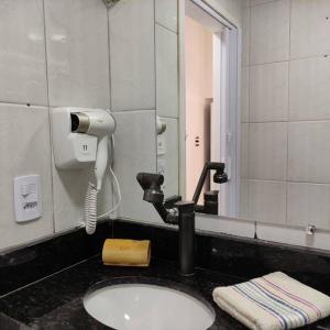 a bathroom sink with a hair dryer and a phone at Kitnet no centro de Guarapari in Guarapari