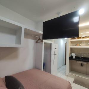 Habitación con cama y TV de pantalla plana. en Kitnet no centro de Guarapari, en Guarapari