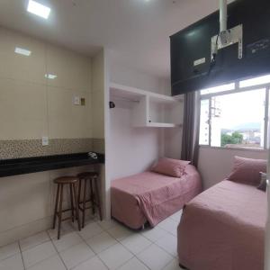Habitación pequeña con 2 camas y cocina en Kitnet no centro de Guarapari, en Guarapari