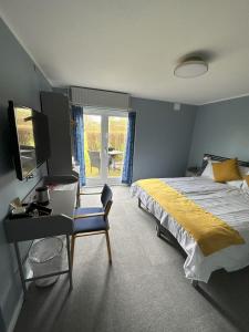 Dormitorio con cama, escritorio y TV en Lynge kro & Hotel 