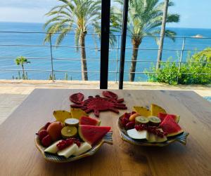 a plate of fruit on a table with a view of the ocean at El jardin Botánico Villa LUZ in Altea