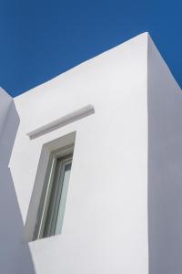 a window on the side of a white building at Maison a la Plage in Faros